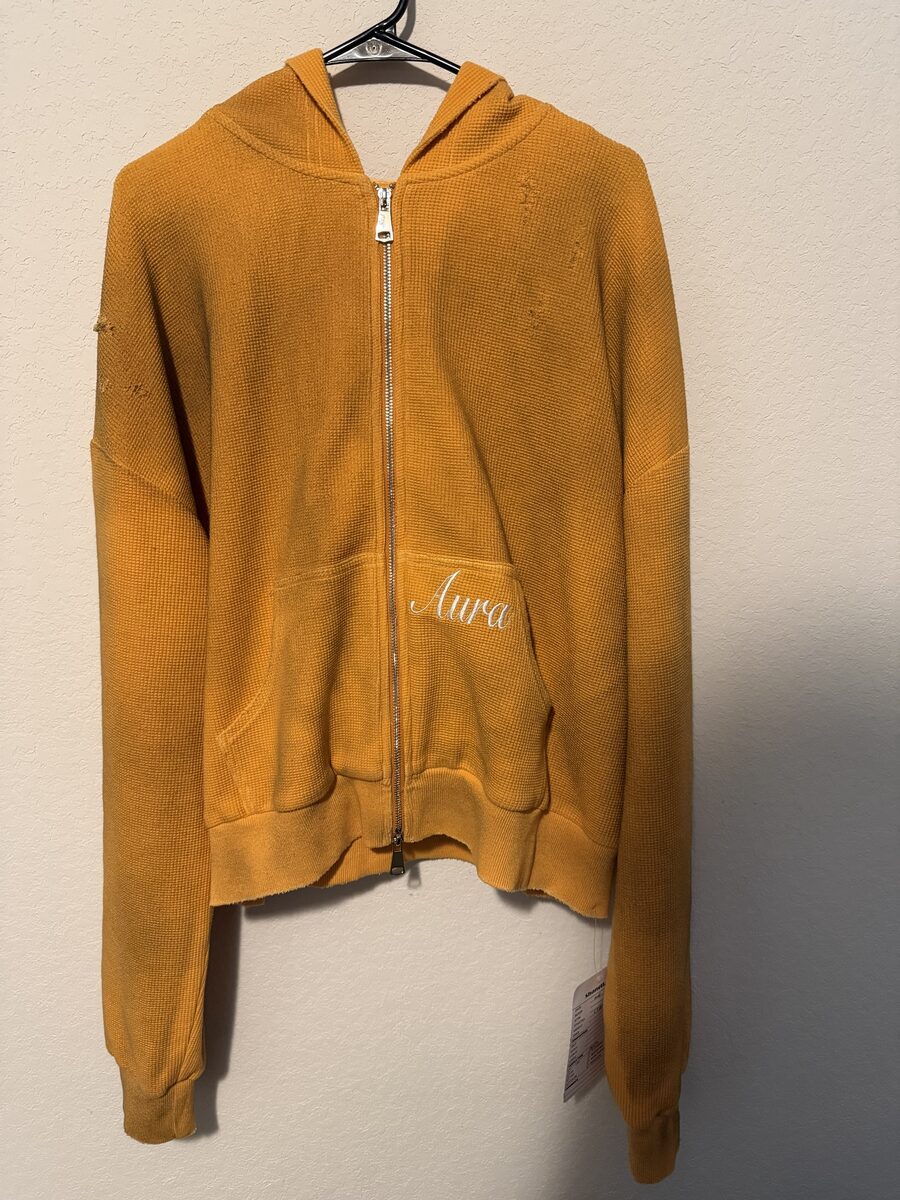 Mustard waffle-knit zip hoodie with distressed details and white 'Aura' script embroidery on the front pocket
